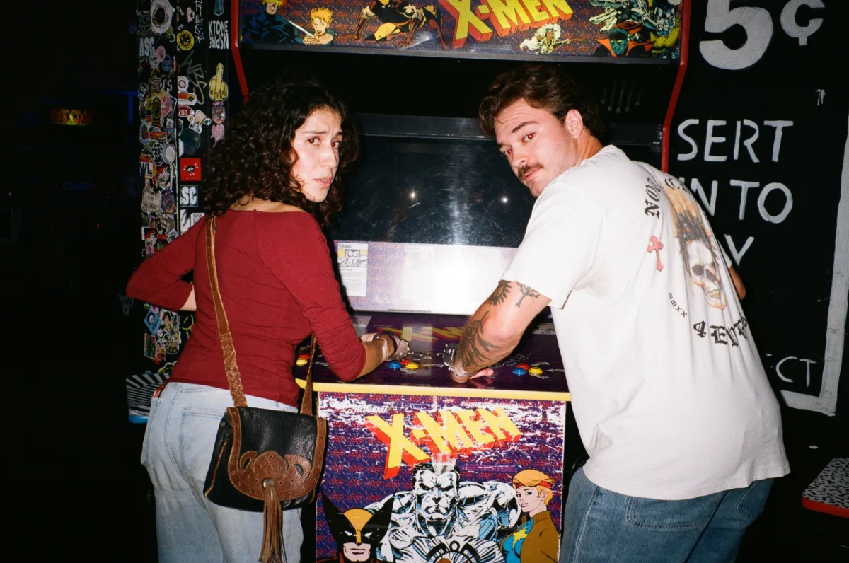 Jack and a friend, handcuffed together, looking back from an X-Men arcade machine