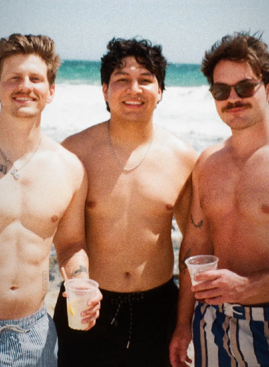 Jack and two friends on the beach, drinks in hand
