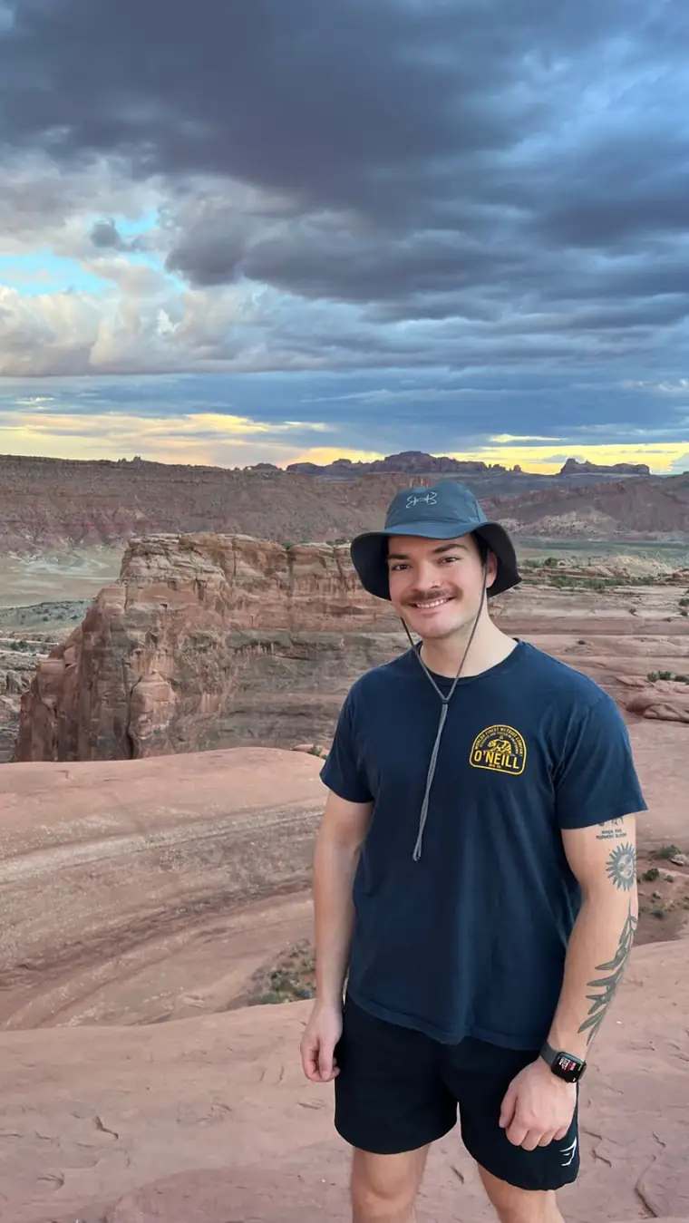 Jack in a bucket hat on red sandstone at sunset